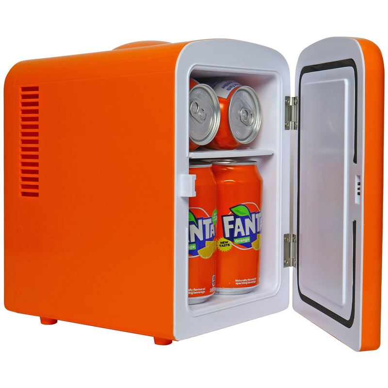 Lifestyle image of Coca-Cola Fanta 6 can mini fridge, closed, on a white desktop with an aqua wall behind. There is a stack of books and a pink camera to the left of the fridge and a bookshelf to the right